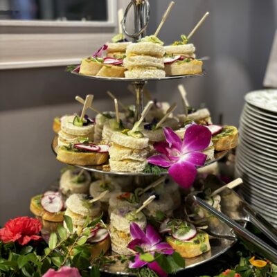 Three tier display if mini tea sandwiches garnished with flowers