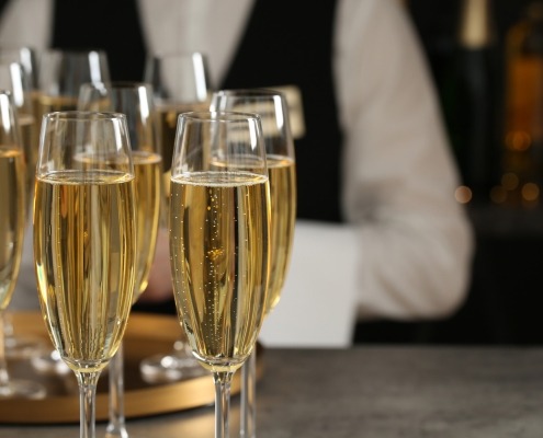 glasses of champagne and waiter in restaurant, closeup. space for text
